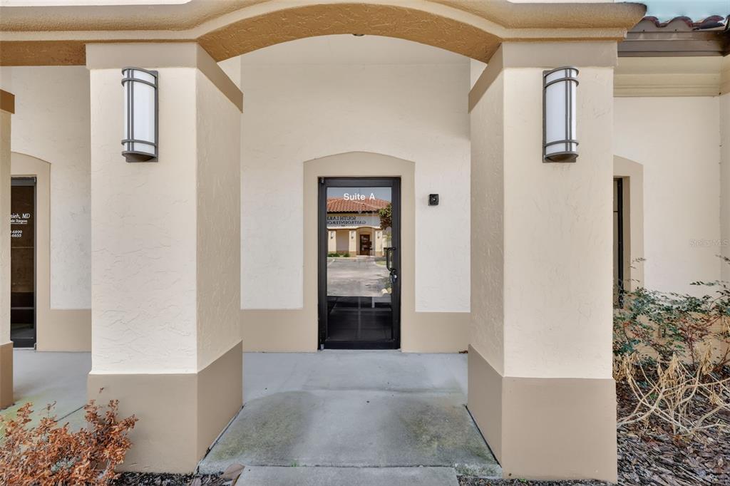 The exterior entrance of a commercial building features a glass door labeled Suite A — 841 OAKLEY SEAVER DRIVE UNIT A, CLERMONT, FL