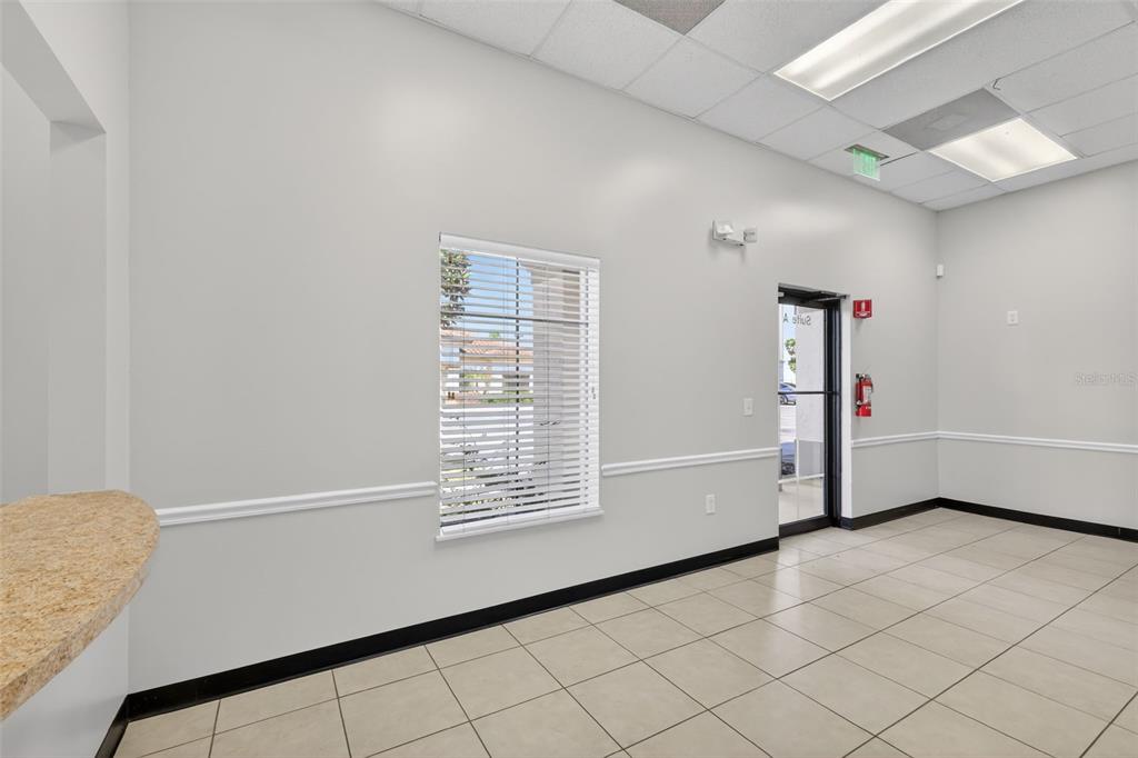 An empty commercial office space with white walls, tile flooring, a window, and a door — 841 OAKLEY SEAVER DRIVE UNIT A, CLERMONT, FL