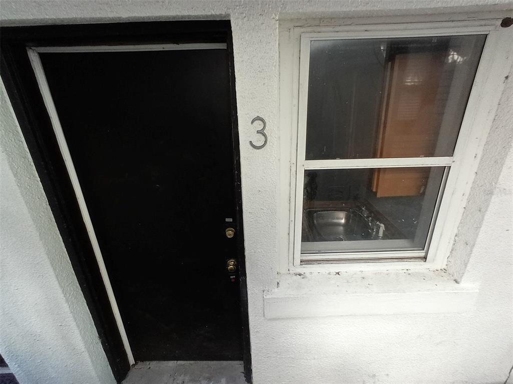 A black door labeled with the number three sits next to a window showing a sink — 704 CORDOVA DRIVE, ORLANDO, FL