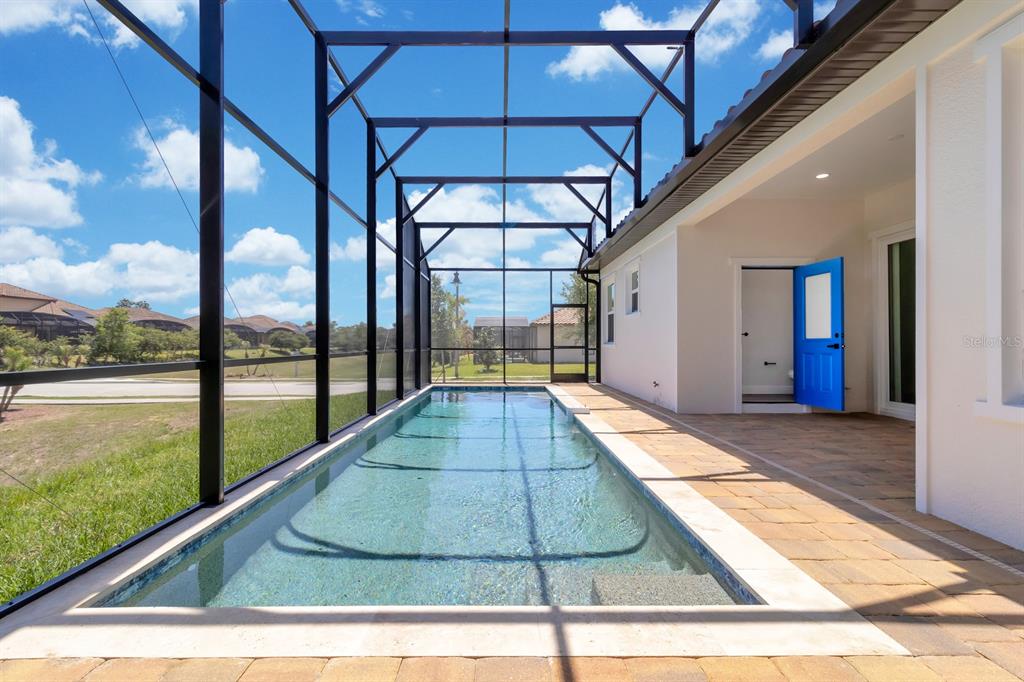 A long rectangular swimming pool enclosed by a black screen cage next to a patio — 376 VILLA SORRENTO CIRCLE, HAINES CITY, FL