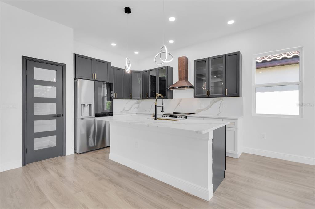 A modern kitchen features dark gray cabinets, a white marble island, and stainless steel appliances — 376 VILLA SORRENTO CIRCLE, HAINES CITY, FL