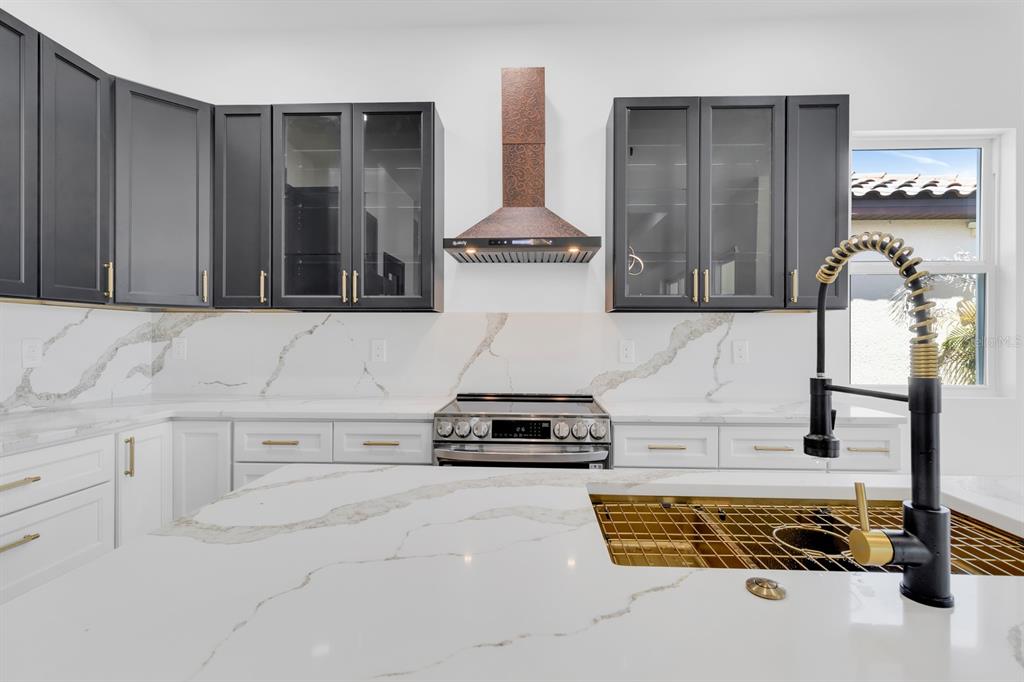 A kitchen features white marble countertops, dark upper cabinets, white lower cabinets, and a copper hood — 376 VILLA SORRENTO CIRCLE, HAINES CITY, FL