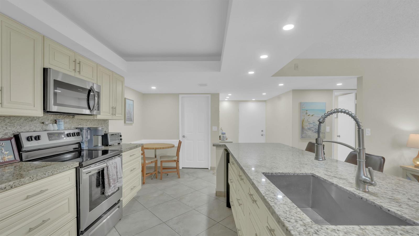 A kitchen features light-colored cabinets, granite countertops, stainless steel appliances, and a central island — 450 Egret Circle # 9207, Delray Beach FL 33444, DELRAY BEACH, FL