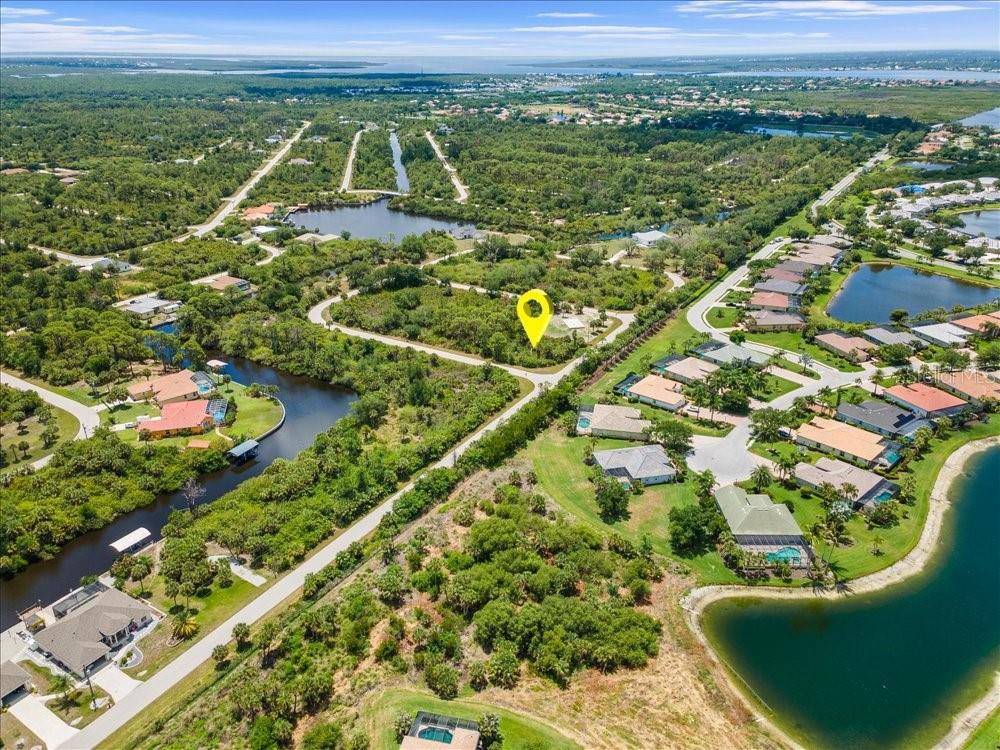 An aerial view shows a vacant, tree-covered lot marked with a yellow pin near water — 2211 HALE STREET, PORT CHARLOTTE, FL
