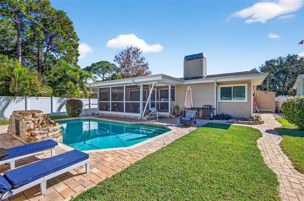 A backyard features a swimming pool, stone water feature, patio, and a screened-in porch — 2366 PEMBROOK DRIVE, CLEARWATER, FL