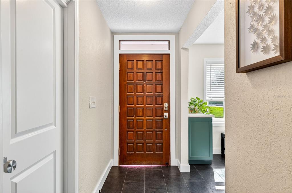 An entryway features a dark wood grid-patterned door, light walls, and dark tile flooring — 2366 PEMBROOK DRIVE, CLEARWATER, FL