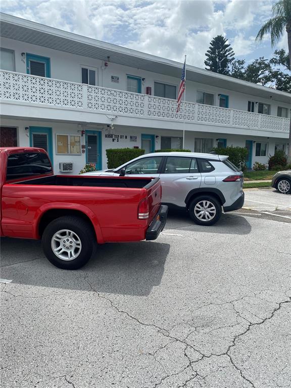 A red pickup truck and a silver SUV are parked in front of an apartment building — 8350 112TH STREET UNIT 104, SEMINOLE, FL