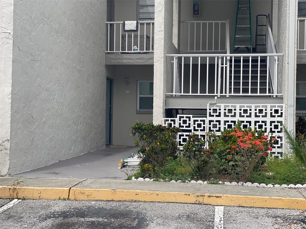 An exterior view shows a ground-level patio, a staircase, and decorative concrete block walls — 2625 STATE ROAD 590 UNIT 2711, CLEARWATER, FL