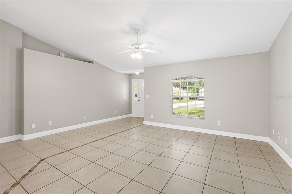 An empty living room features light gray walls, large beige floor tiles, and a ceiling fan — 39 PINWHEEL LANE, PALM COAST, FL