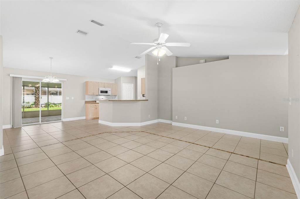An open-concept living and dining area features light tile flooring and a kitchen with cabinets — 39 PINWHEEL LANE, PALM COAST, FL