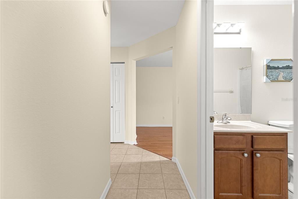 A tiled hallway leads to a bathroom with a wood vanity and a carpeted room — 9770 SW 92ND PLACE ROAD, OCALA, FL