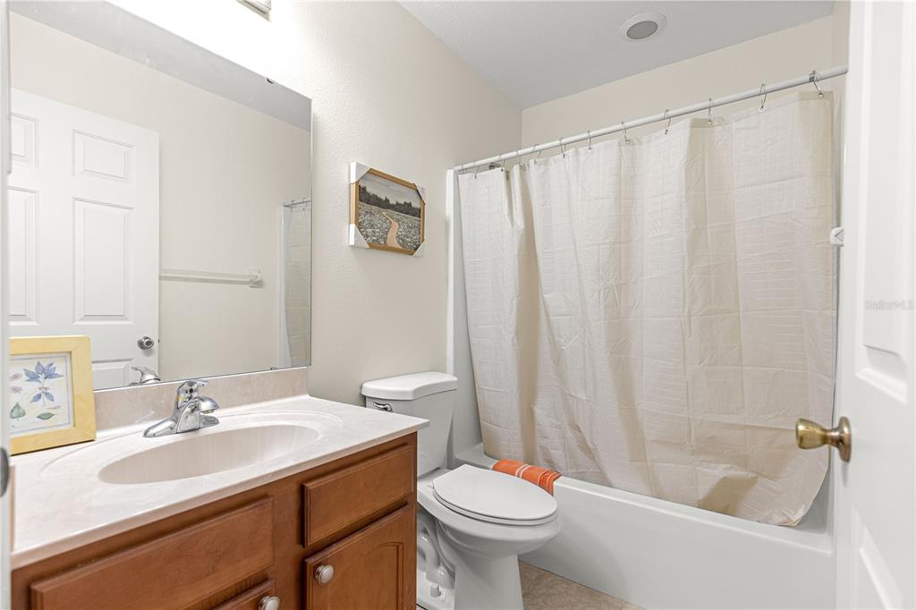 A bathroom features a wooden vanity, a toilet, and a shower-tub combination with a curtain — 9770 SW 92ND PLACE ROAD, OCALA, FL