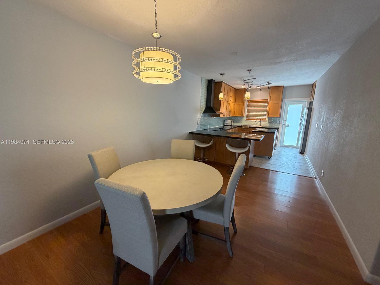 A dining area with a round table and chairs sits adjacent to an open kitchen — 630 Layne Blvd # 215, Hallandale Beach FL 33009, HALLANDALE BEACH, FL