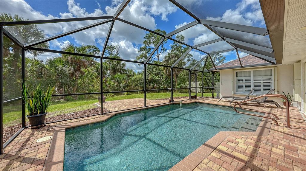 A screened-in swimming pool with a brick paver deck and a view of lush landscaping — 2051 SNOVER AVENUE, NORTH PORT, FL