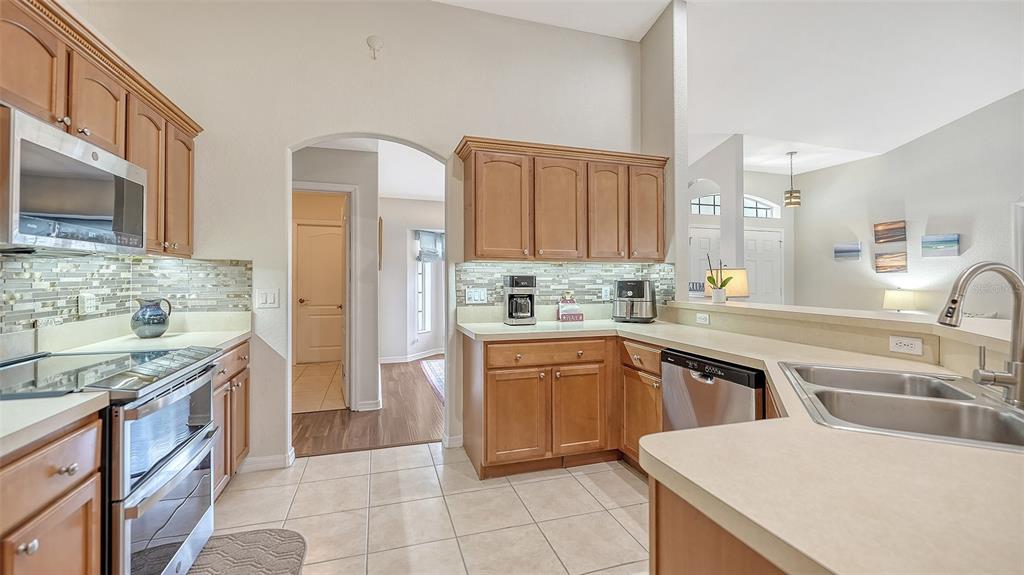 A kitchen with wood cabinets, stainless steel appliances, tile flooring, and a breakfast bar — 2051 SNOVER AVENUE, NORTH PORT, FL