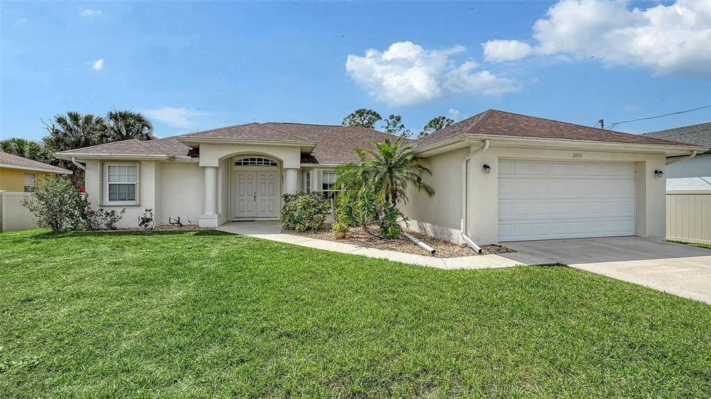A single-story house with a white exterior, a two-car garage, and a grassy front yard — 2051 SNOVER AVENUE, NORTH PORT, FL