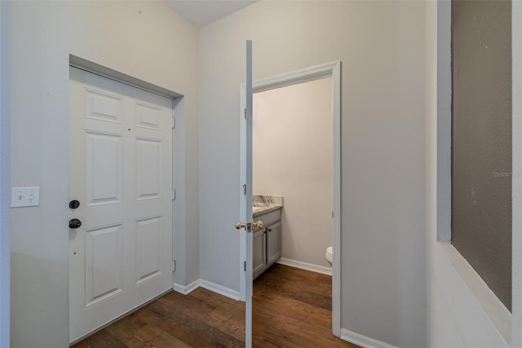 A white door opens to a small bathroom with a vanity and wood-look flooring — 6417 ROSEFINCH COURT UNIT 102, LAKEWOOD RANCH, FL