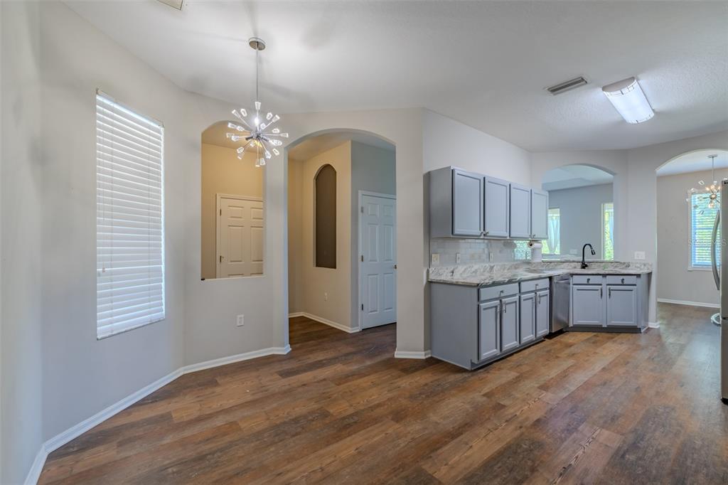 A kitchen and dining area feature gray cabinets, granite countertops, and wood-look flooring — 6417 ROSEFINCH COURT UNIT 102, LAKEWOOD RANCH, FL