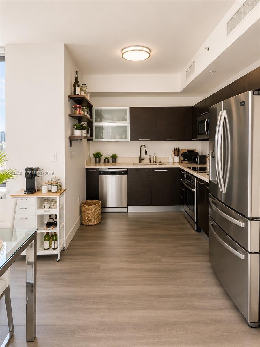 A modern kitchen features dark wood cabinets, stainless steel appliances, and light-colored flooring — 90 SW 3rd St # 1413, Miami FL 33130, MIAMI, FL