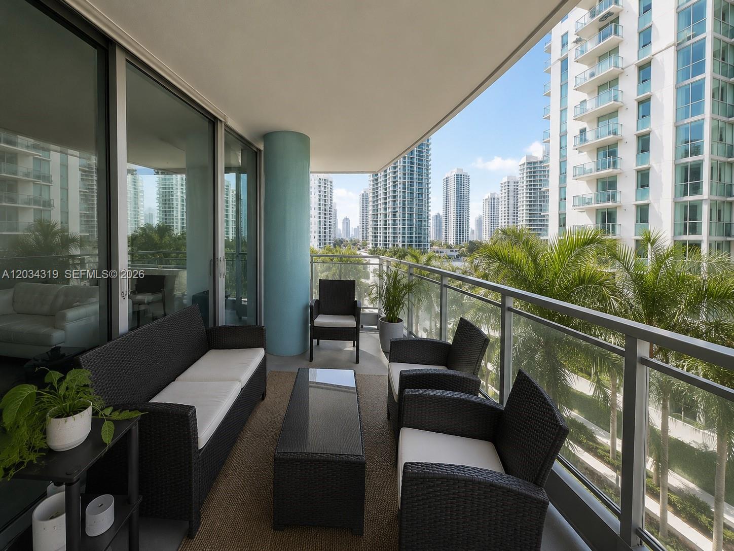 A furnished balcony features a sofa, chairs, a coffee table, and views of city buildings — 90 SW 3rd St # 1413, Miami FL 33130, MIAMI, FL