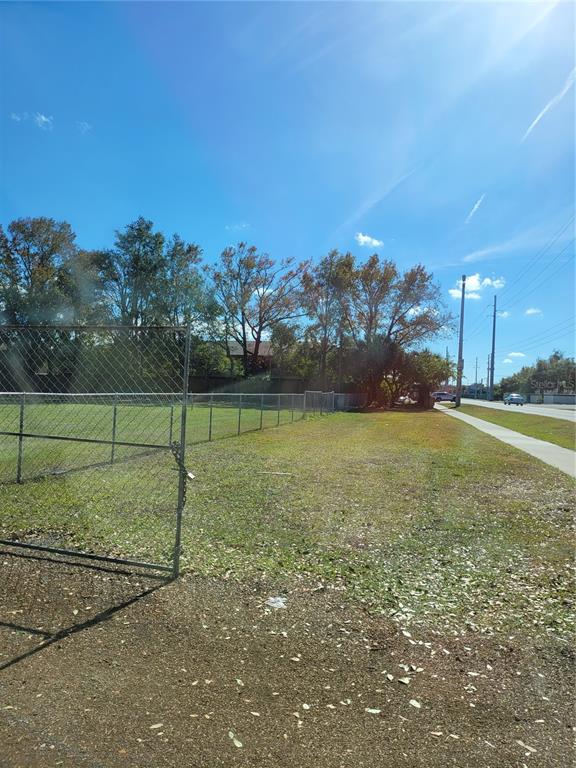 A chain-link fence borders a vacant grassy lot next to a sidewalk and road — 5721 S TEXAS AVENUE, ORLANDO, FL