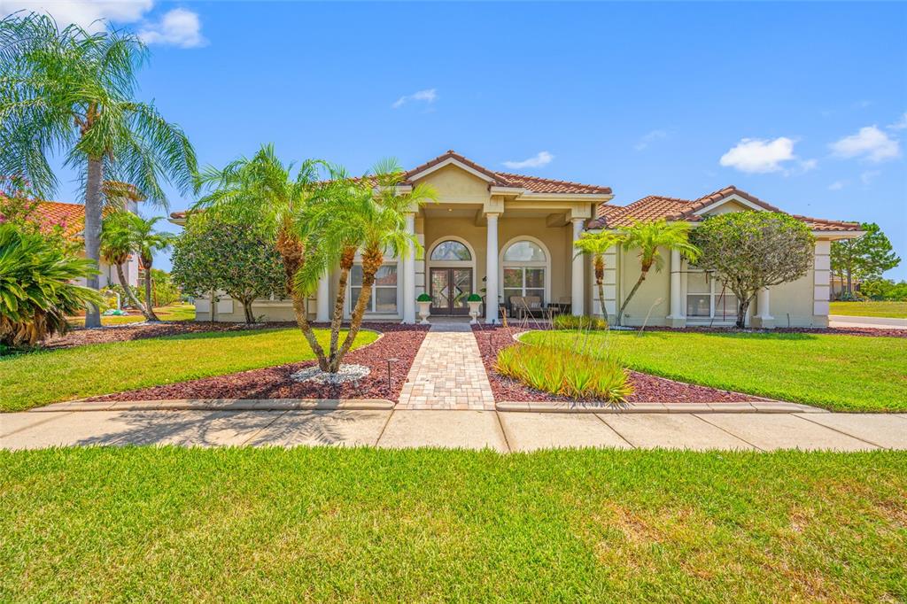 A single-story house with a tiled roof, columns, and a paved walkway through the lawn — 9801 COMPASS POINT WAY, TAMPA, FL