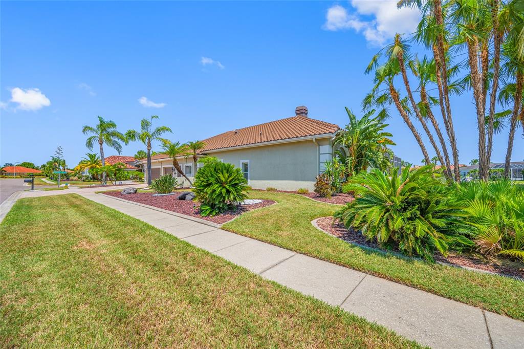 A side view of a house with a tiled roof, landscaping, and a concrete sidewalk — 9801 COMPASS POINT WAY, TAMPA, FL