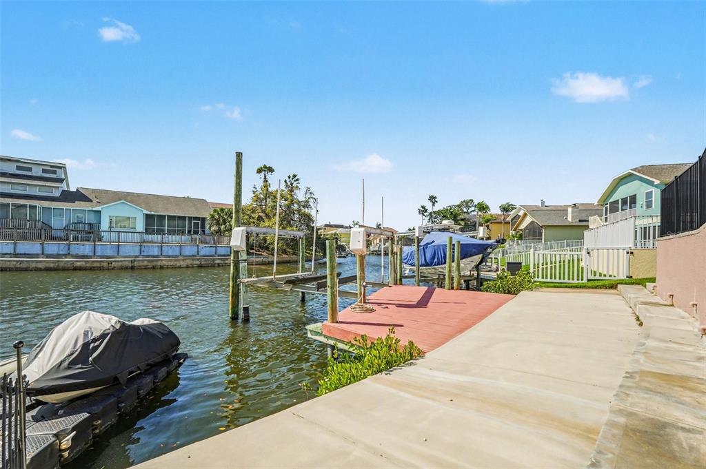 A concrete patio overlooks a canal with a boat lift, a dock, and a jet ski — 6340 SPOONBILL DRIVE, NEW PORT RICHEY, FL