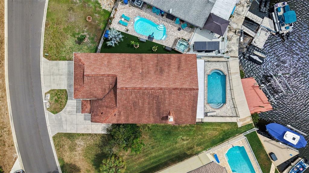 An aerial view shows a house with a red roof, two pools, and a boat dock — 6340 SPOONBILL DRIVE, NEW PORT RICHEY, FL