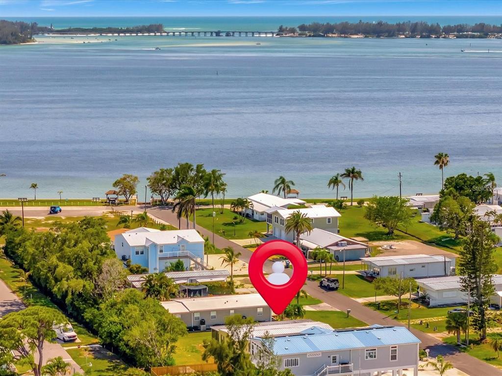 An aerial view shows a coastal neighborhood with houses near a bay and a bridge — 4511 106TH STREET W, BRADENTON, FL