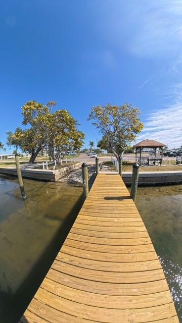 A wooden dock extends over the water toward a grassy area with trees and a gazebo — 4511 106TH STREET W, BRADENTON, FL