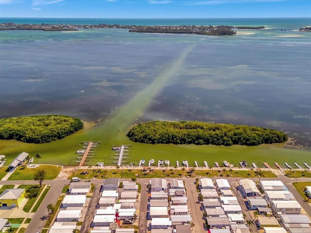 An aerial view shows a waterfront mobile home community with docks extending into the bay — 4511 106TH STREET W, BRADENTON, FL