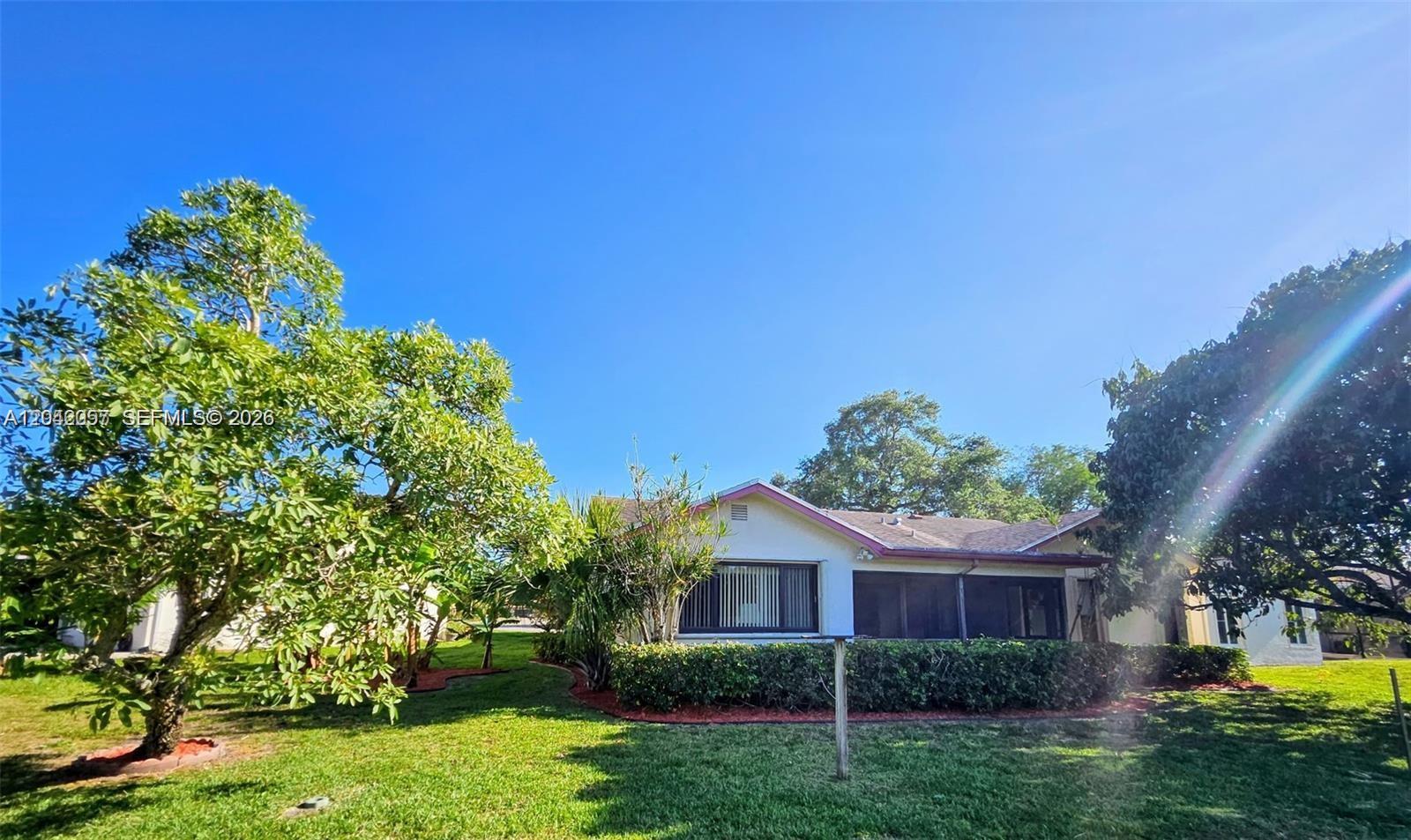 A single-story house with a screened-in porch sits on a grassy lot with trees — 10301 Greenbriar Ct, Boca Raton FL 33498, BOCA RATON, FL