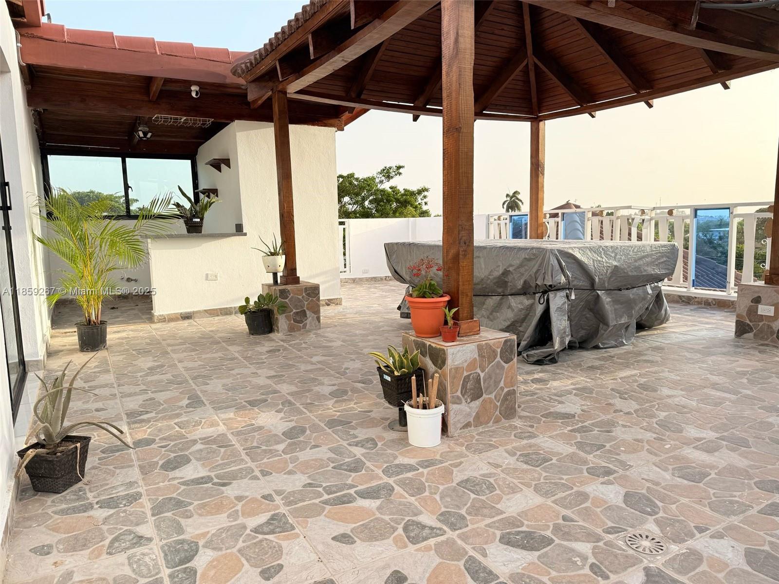 A rooftop patio features a wooden gazebo, stone-patterned tile flooring, and a covered outdoor table — San Jose # 24 San Jose #24, DR, DR