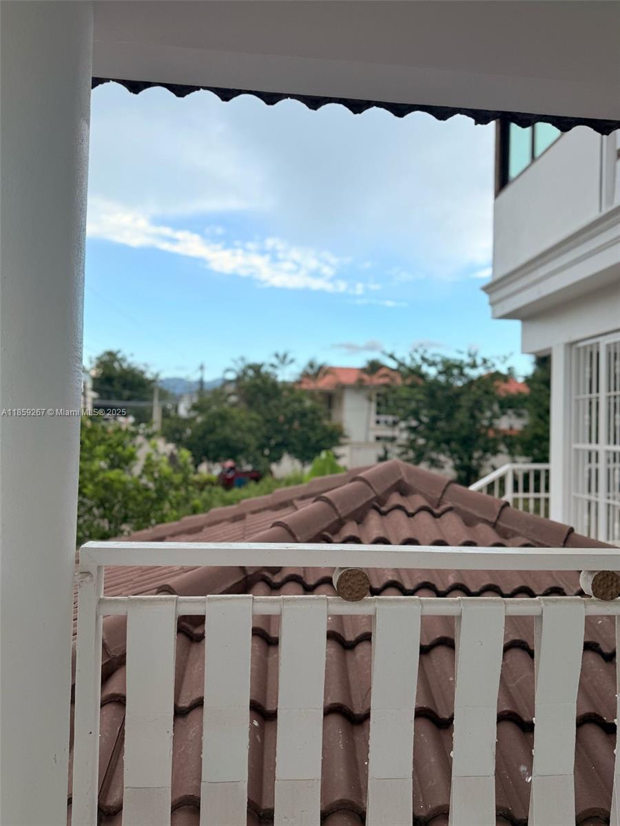 A view from a balcony overlooks a tiled roof and surrounding trees under a blue sky — San Jose # 24 San Jose #24, DR, DR