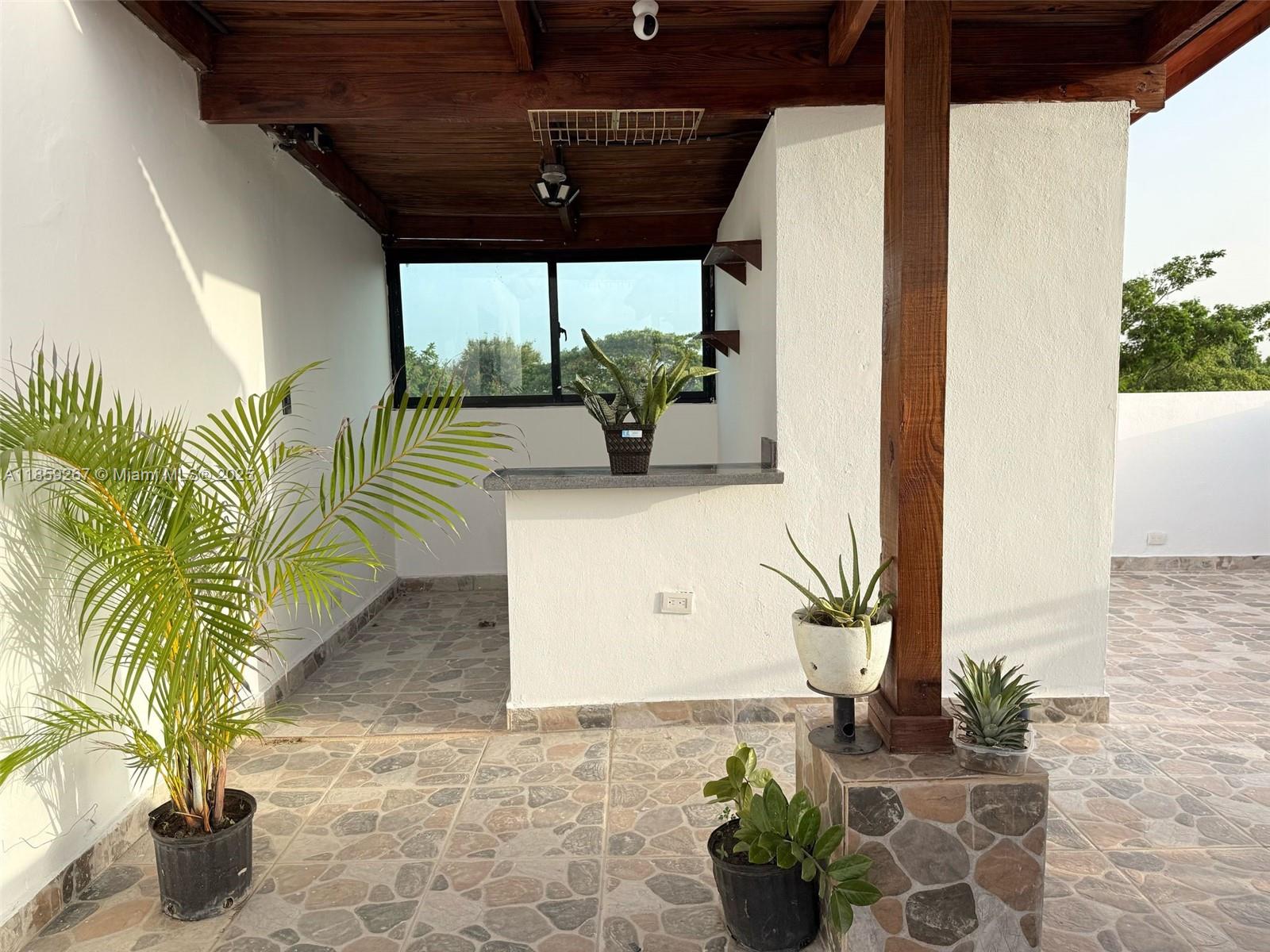 A covered outdoor patio features a stone-tiled floor, a small bar area, and potted plants — San Jose # 24 San Jose #24, DR, DR