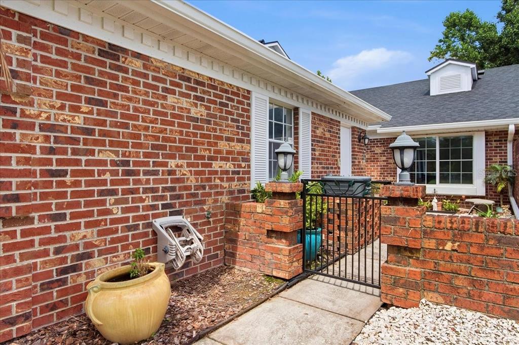 A brick exterior features a gated courtyard entrance with two lamp posts and a planter — 1429 S CHICKASAW TRAIL UNIT 7, ORLANDO, FL