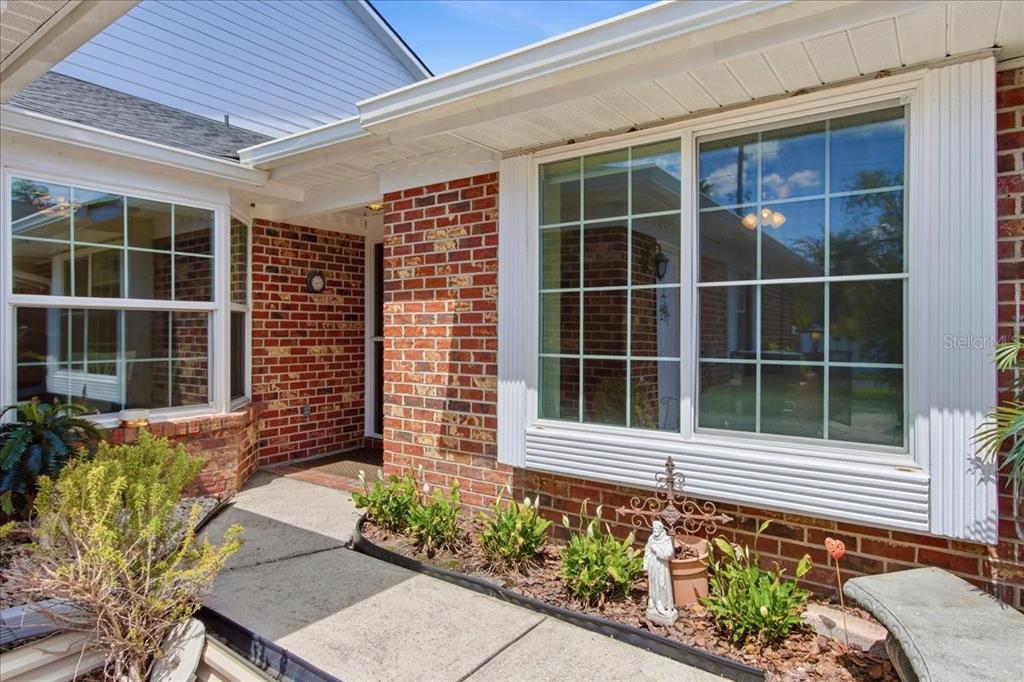A brick house exterior features a concrete walkway leading to an entrance near large windows — 1429 S CHICKASAW TRAIL UNIT 7, ORLANDO, FL