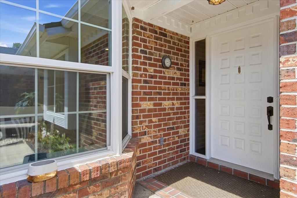A brick exterior entryway features a white front door, a bay window, and a mat — 1429 S CHICKASAW TRAIL UNIT 7, ORLANDO, FL