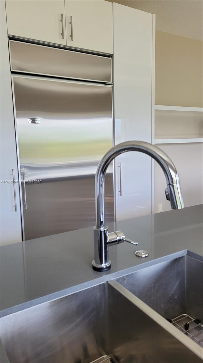 A modern kitchen features a stainless steel refrigerator, white cabinetry, and a chrome faucet — 8780 SW 223rd Ter # 8780, Cutler Bay FL 33190, CUTLER BAY, FL