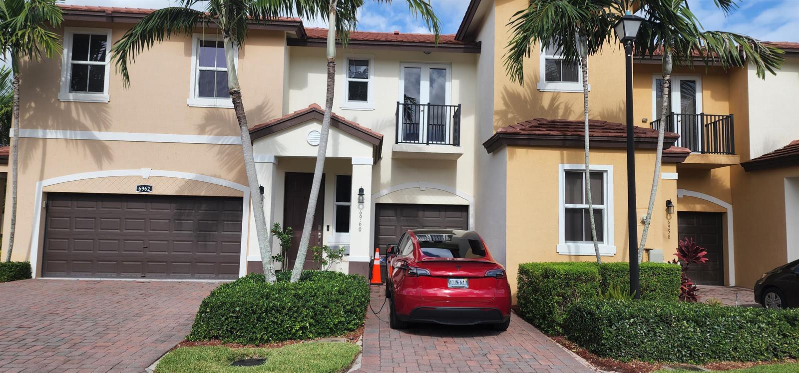 A bright entryway features a glass console table, a shoe rack, and a white door — 6960 Long Pine Circle, Coconut Creek FL 33073, COCONUT CREEK, FL