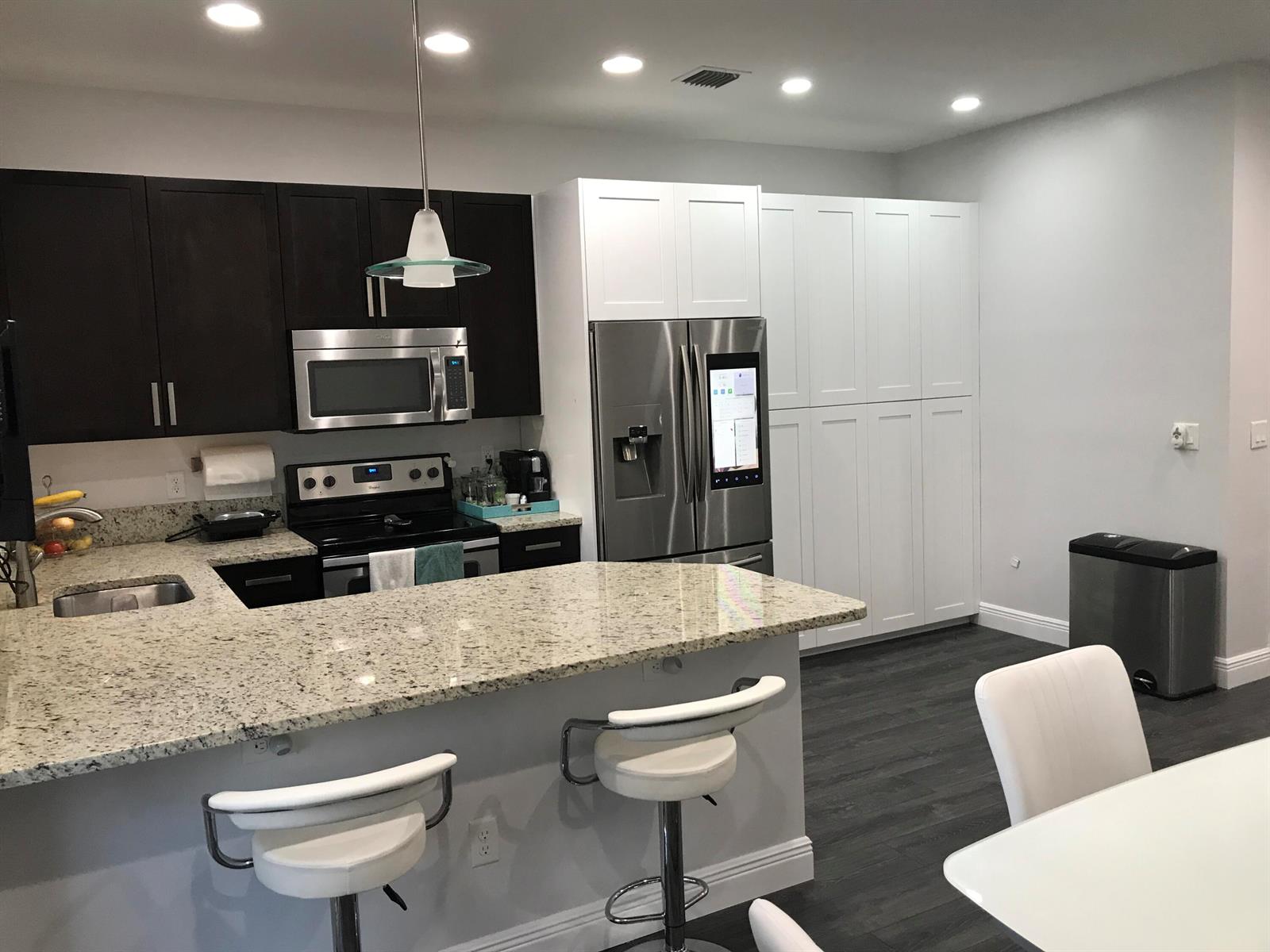 A living room features a wall-mounted television, a blue area rug, and a glass coffee table — 6960 Long Pine Circle, Coconut Creek FL 33073, COCONUT CREEK, FL