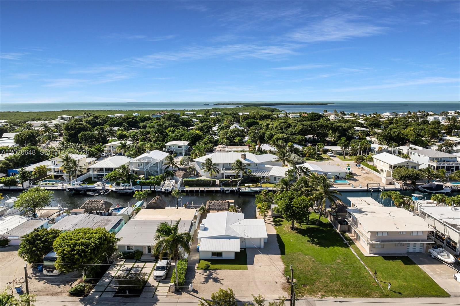 An aerial view shows waterfront houses with boat docks along a canal near the ocean — 251 Azalea St, Plantation Key FL 33070, PLANTATION KEY, FL