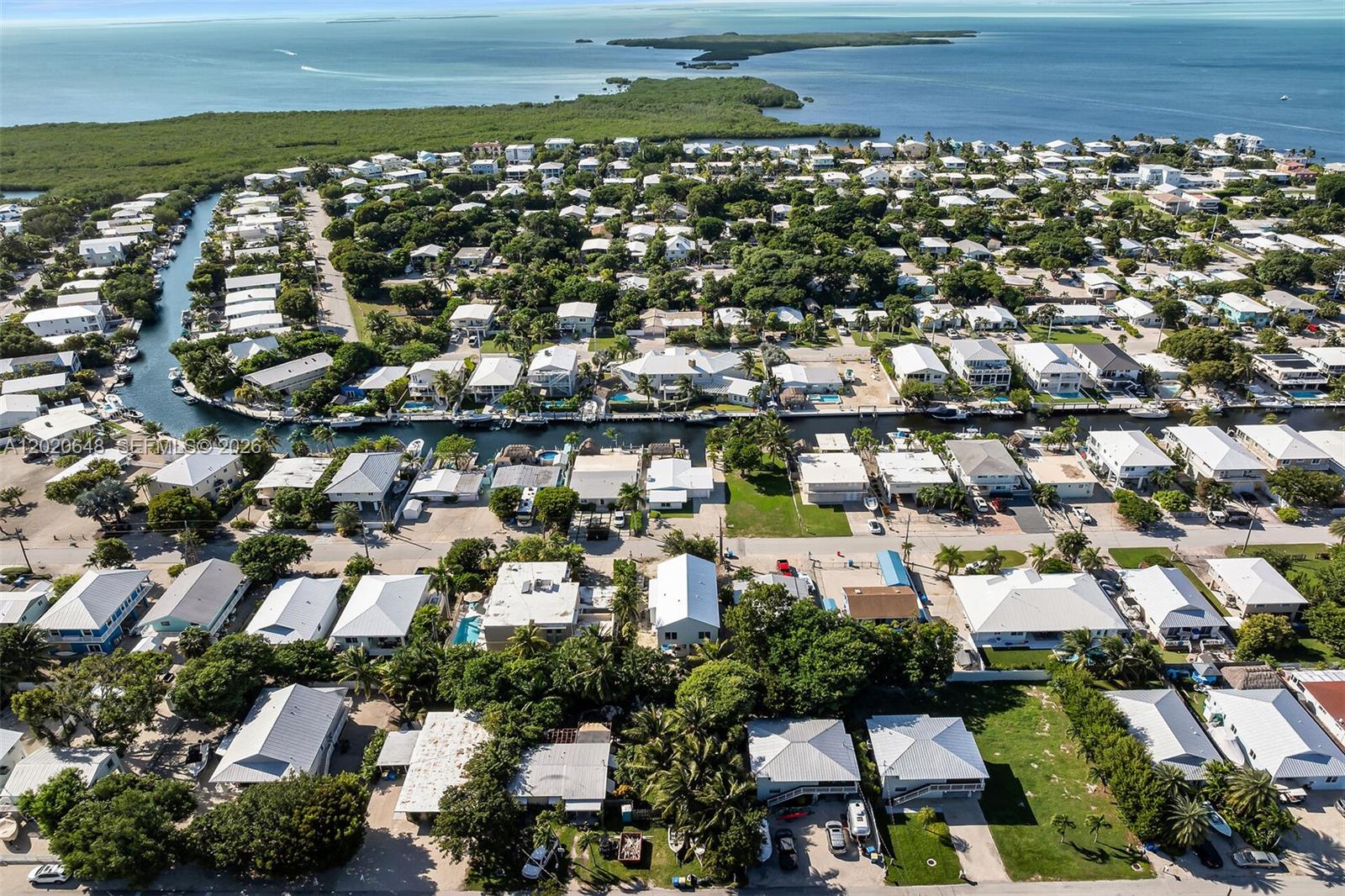 An aerial view shows a residential neighborhood with houses, canals, and lush vegetation near water — 251 Azalea St, Plantation Key FL 33070, PLANTATION KEY, FL