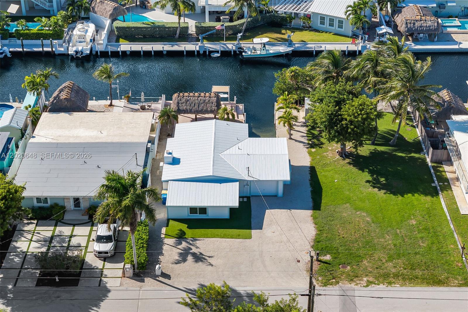 An aerial view shows a light blue house with a metal roof and a canal — 251 Azalea St, Plantation Key FL 33070, PLANTATION KEY, FL