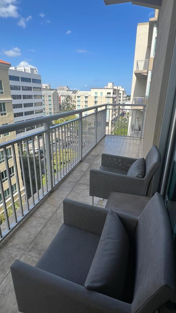 A balcony with two gray chairs and a small table overlooks a city street — 9066 SW 73rd Ct # 607, Miami FL 33156, MIAMI, FL