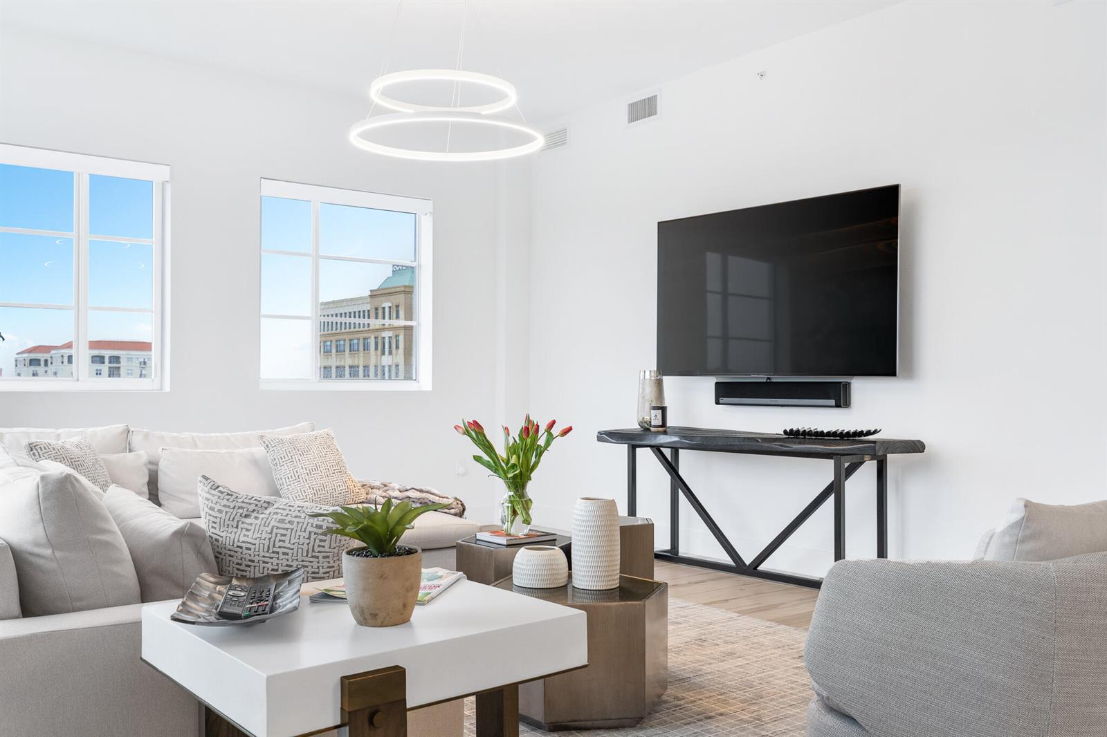 A bright living room features a white sofa, a television, and a modern light fixture — 155 E Boca Raton Road # 623, Boca Raton FL 33432, BOCA RATON, FL