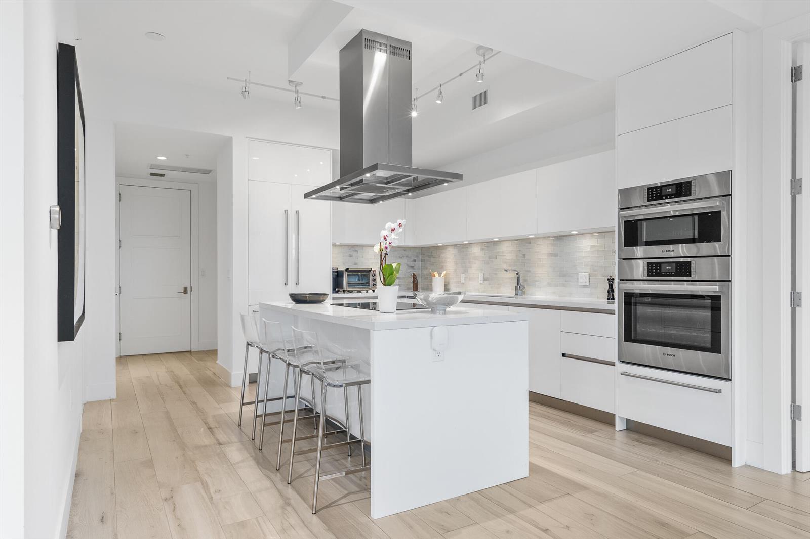 A modern white kitchen features a central island with bar stools and stainless steel appliances — 155 E Boca Raton Road # 623, Boca Raton FL 33432, BOCA RATON, FL