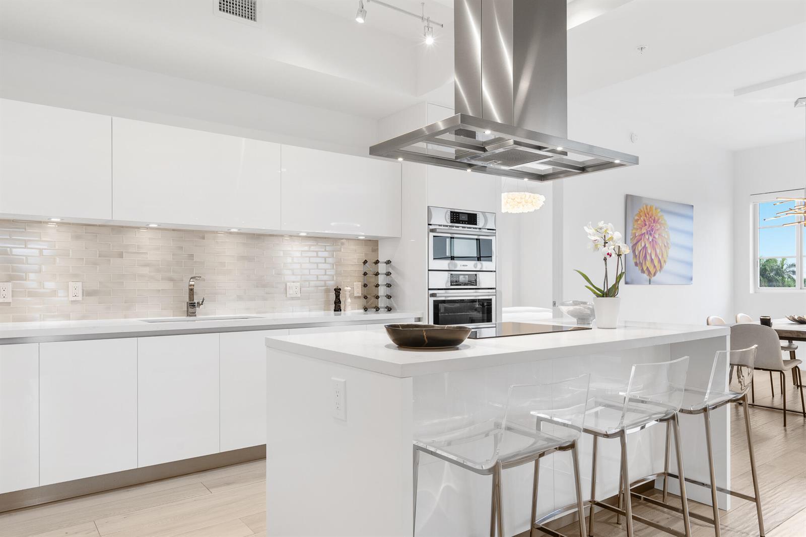 A modern white kitchen features a central island with bar stools and stainless steel appliances — 155 E Boca Raton Road # 623, Boca Raton FL 33432, BOCA RATON, FL