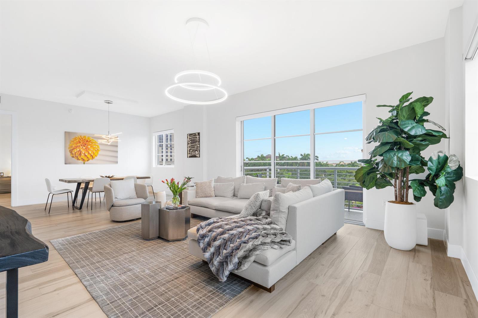 A bright, open-concept living and dining area features light wood floors, modern furniture, and balcony views — 155 E Boca Raton Road # 623, Boca Raton FL 33432, BOCA RATON, FL